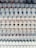 A close-up view of several spiral-bound notebooks stacked vertically, showcasing the overlapping rings and edges of the pages. The spirals are white, and various colors from the notebook covers and pages peek through the spaces between them.