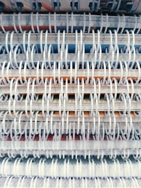 A close-up view of several spiral-bound notebooks stacked vertically, showcasing the overlapping rings and edges of the pages. The spirals are white, and various colors from the notebook covers and pages peek through the spaces between them.