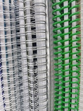 Several spiral-bound notebooks are stacked vertically, showcasing a variety of colors in the spiral bindings ranging from white and gray to vivid green. The pages inside have lined paper, creating a neat and organized appearance.