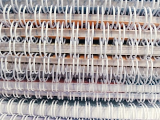 A close-up view of multiple spiral-bound notebooks stacked together, emphasizing the intertwined spiral bindings.