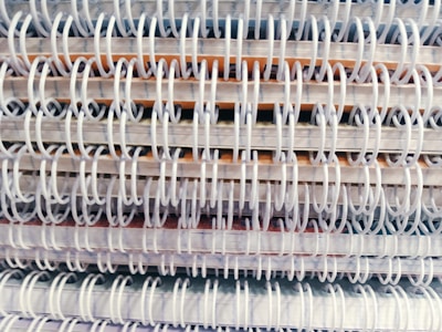 A close-up view of multiple spiral-bound notebooks stacked together, emphasizing the intertwined spiral bindings.