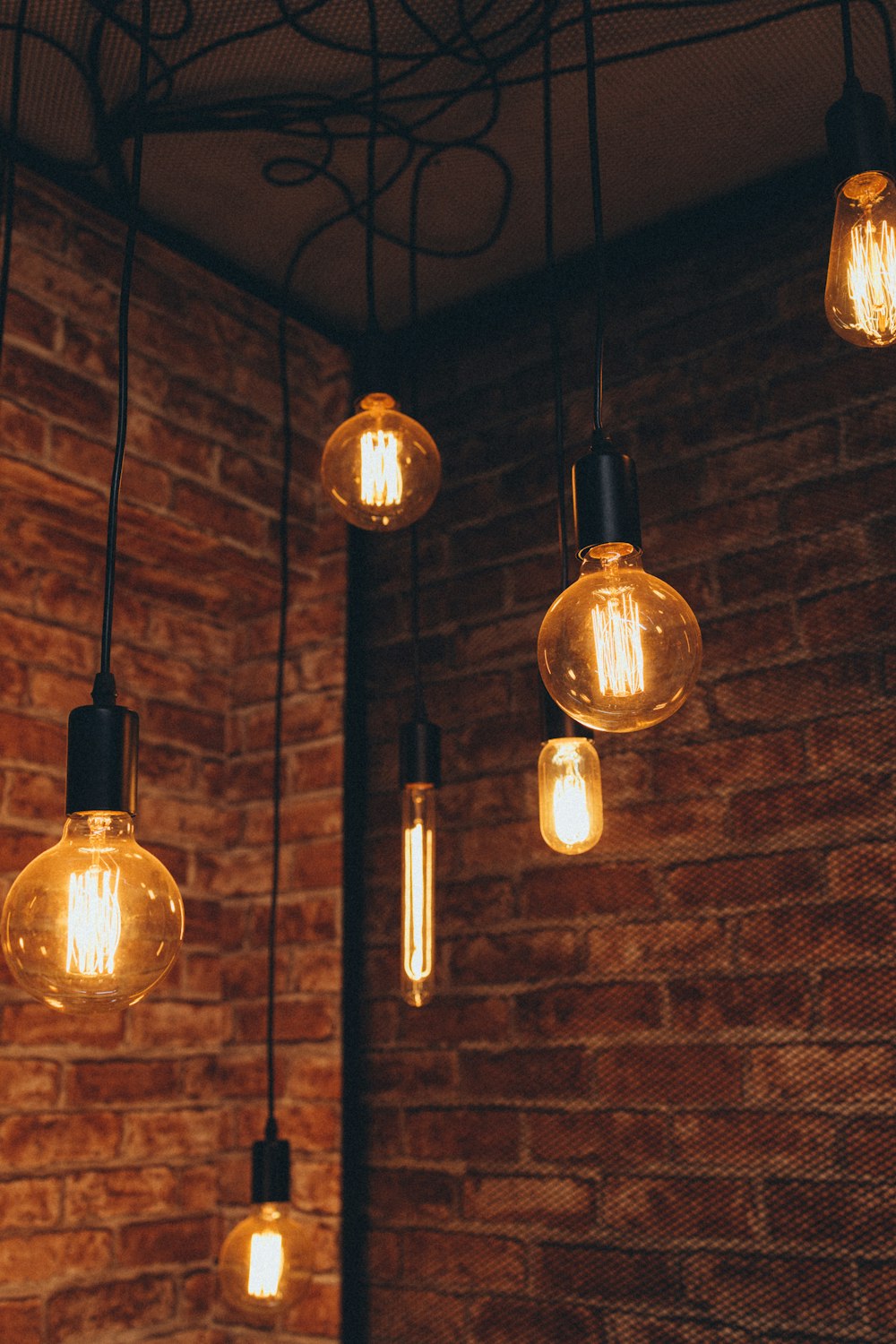 a bunch of light bulbs hanging from a brick wall