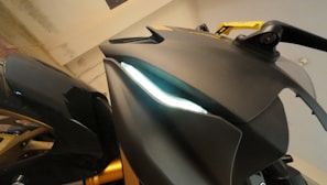 Close-up of a matte black sportbike's aggressive front fairing under moody lighting.