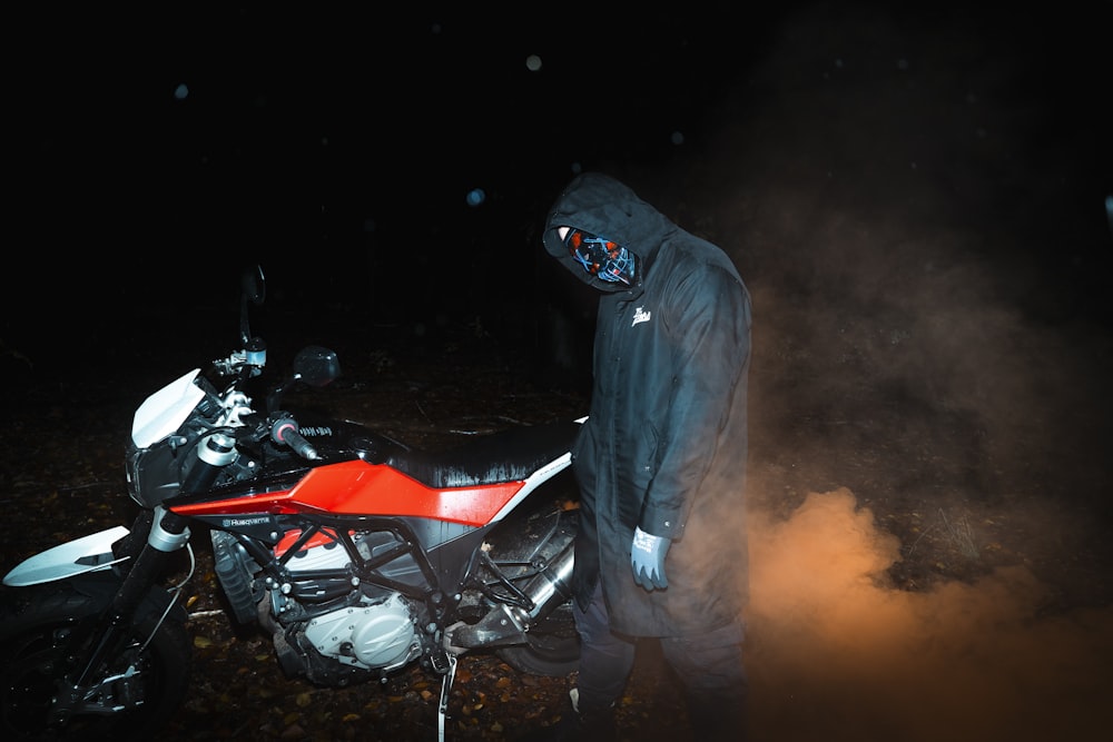 um homem parado ao lado de uma motocicleta no escuro