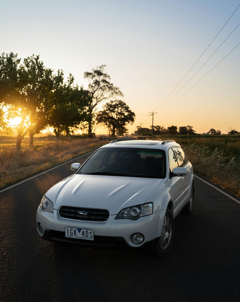 a white car is driving down the road