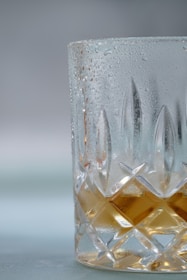 Close-up of a chilled glass of amber beer with condensation, set against a backdrop of South Asian cultural motifs.