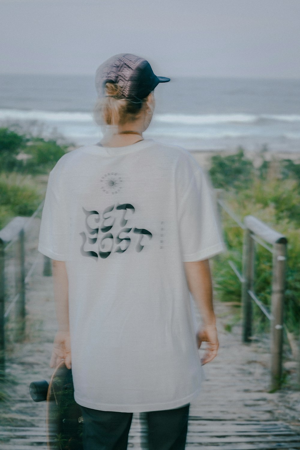 a man holding a skateboard on a wooden walkway