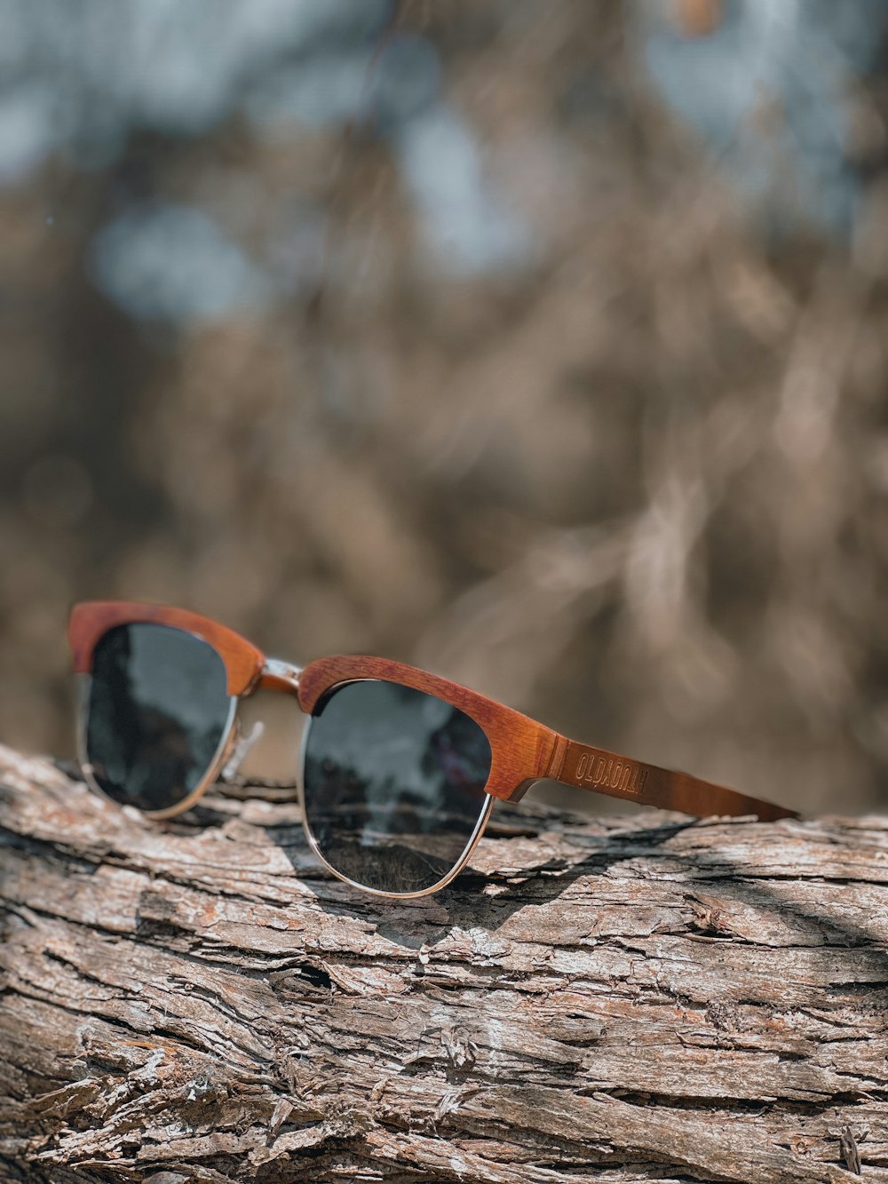 a pair of sunglasses sitting on top of a piece of wood