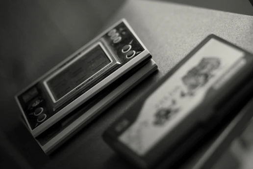 A close-up of a Game Boy Advance SP with a classic retro game on the screen, resting on a wooden table.