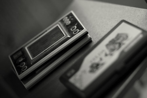 Close-up image of retro handheld gaming devices including Game Boy and Sega Game Gear.