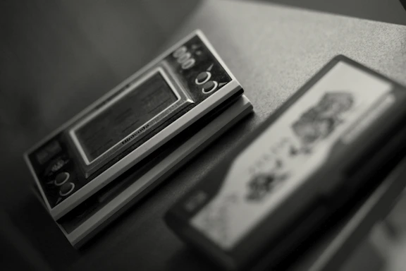 A close-up of vintage game cartridges stacked neatly beside a laptop on a factory desk.