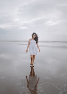 A gentle breeze lifting the hem of a flowing peach dress as a woman walks barefoot through a meadow.
