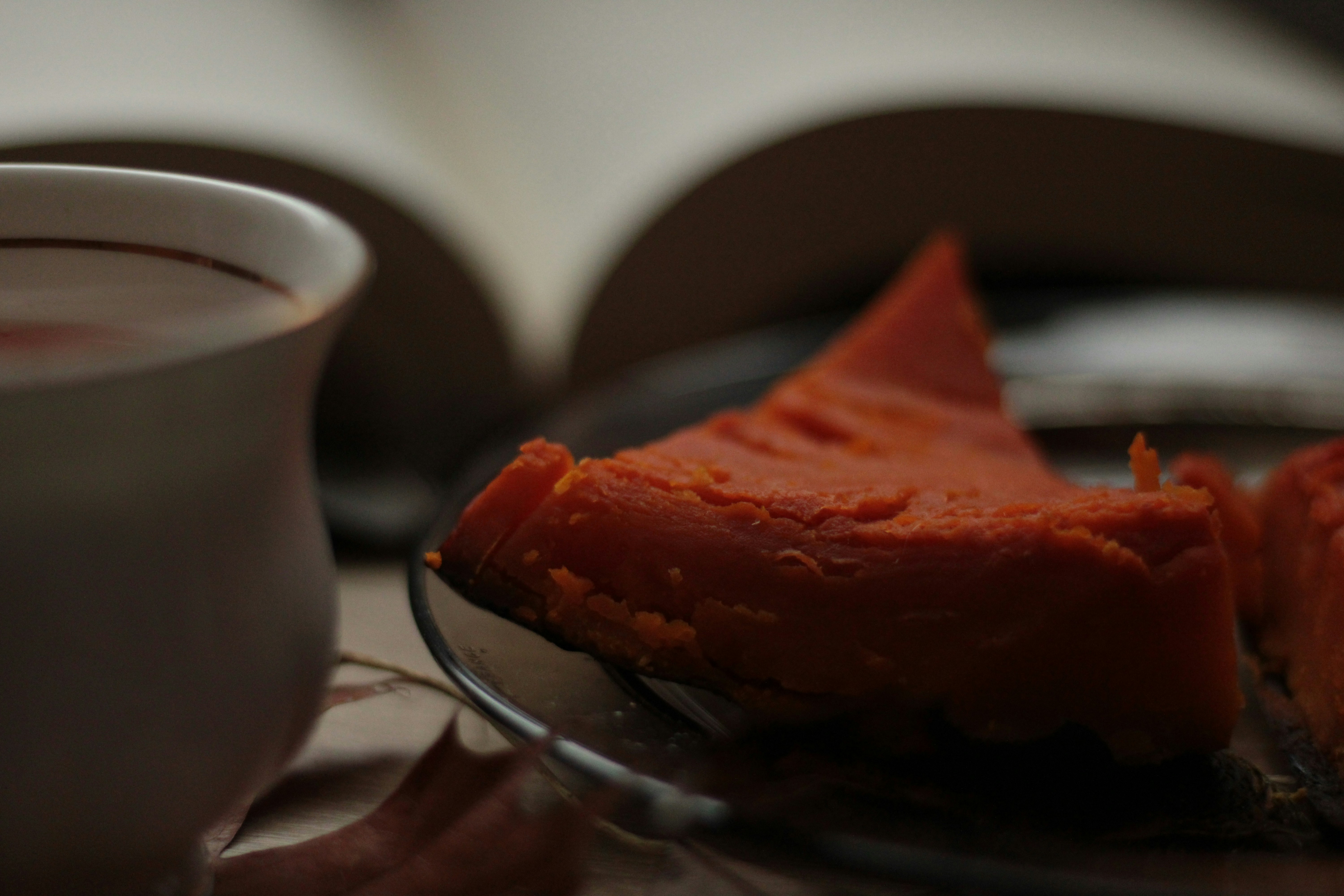 a piece of food on a plate next to a cup of coffee