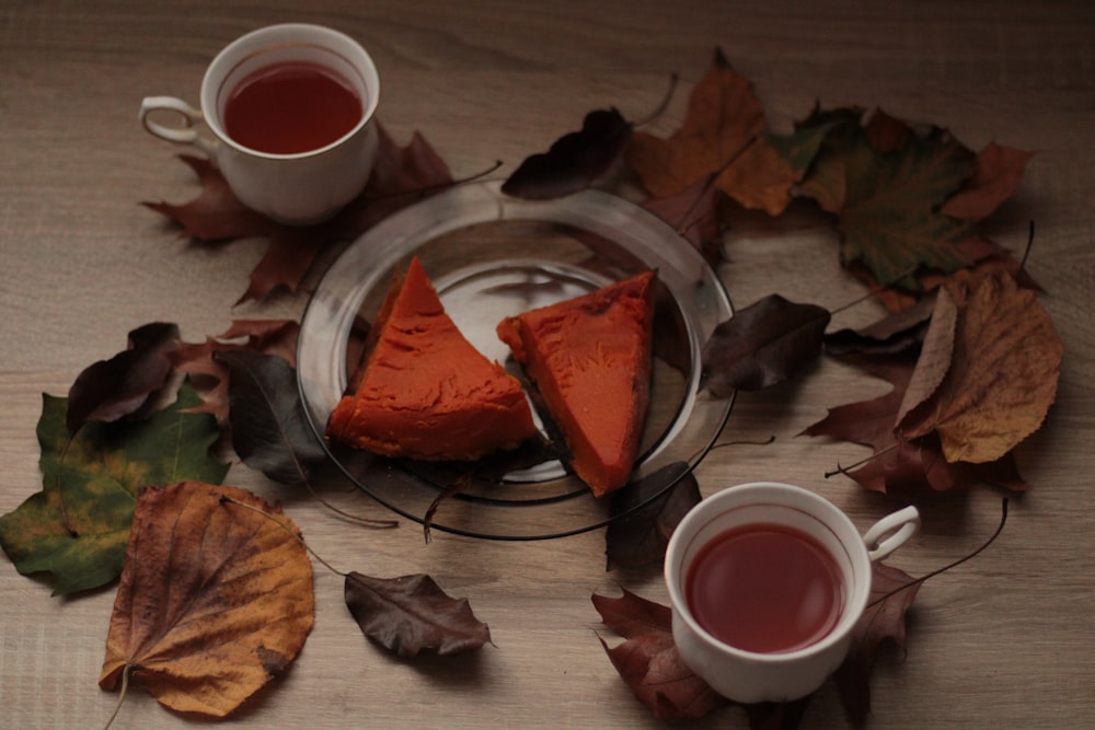 two cups of tea and some leaves on a table