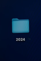 A computer screen displays a digital folder with a light blue color. Below the folder, the number '2024' is prominently shown in white text.