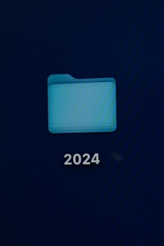 A computer screen displays a digital folder with a light blue color. Below the folder, the number '2024' is prominently shown in white text.
