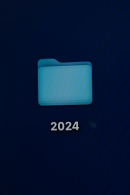 A computer screen displays a digital folder with a light blue color. Below the folder, the number '2024' is prominently shown in white text.