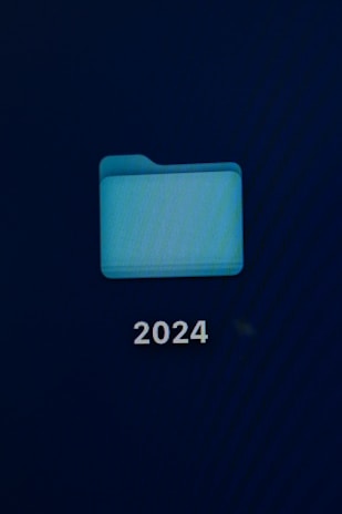 A computer screen displays a digital folder with a light blue color. Below the folder, the number '2024' is prominently shown in white text.