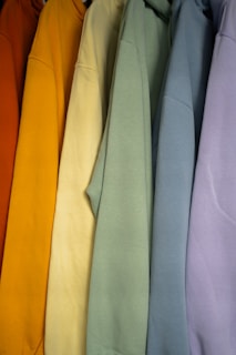 a row of different colored sweatshirts hanging on a rack