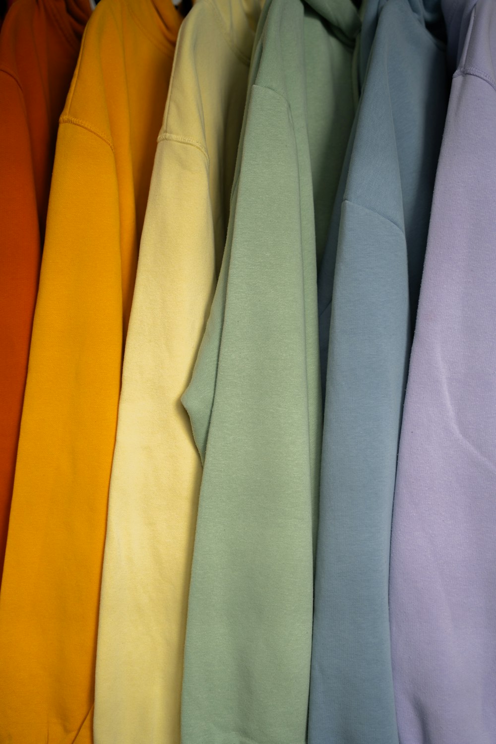 a row of different colored sweatshirts hanging on a rack