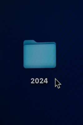A digital blue folder icon labeled '2024' is displayed against a dark background, with a computer mouse cursor nearby.