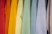 Close-up of soft, bright t-shirts hanging on a rack with natural light highlighting their colors