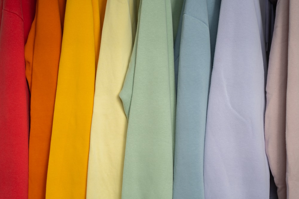 a bunch of different colored shirts hanging on a rack