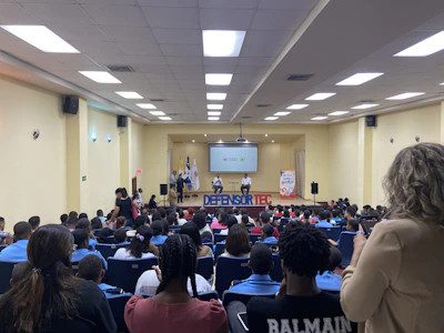 A speaker passionately addressing a diverse audience in a bright conference hall.