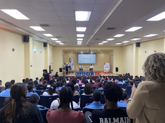 People attending a seminar with a speaker presenting on stage in a modern venue.