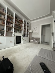 A cozy common room featuring comfortable chairs and a bookshelf filled with books.