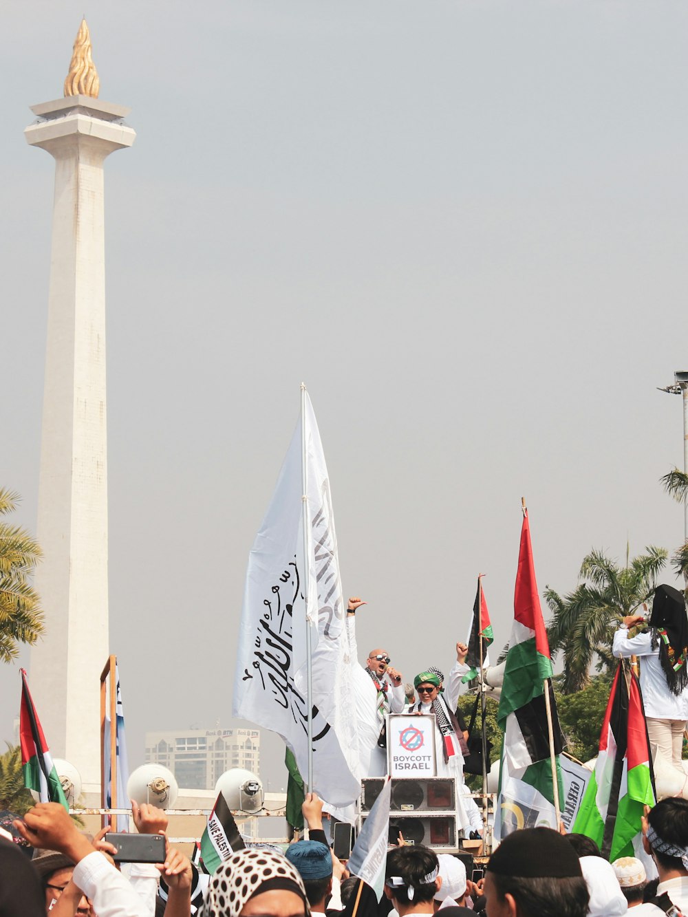 um grande grupo de pessoas segurando bandeiras em frente a um monumento