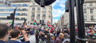 Crowd gathered at a Karachi street protest, red banners waving under a cloudy sky.