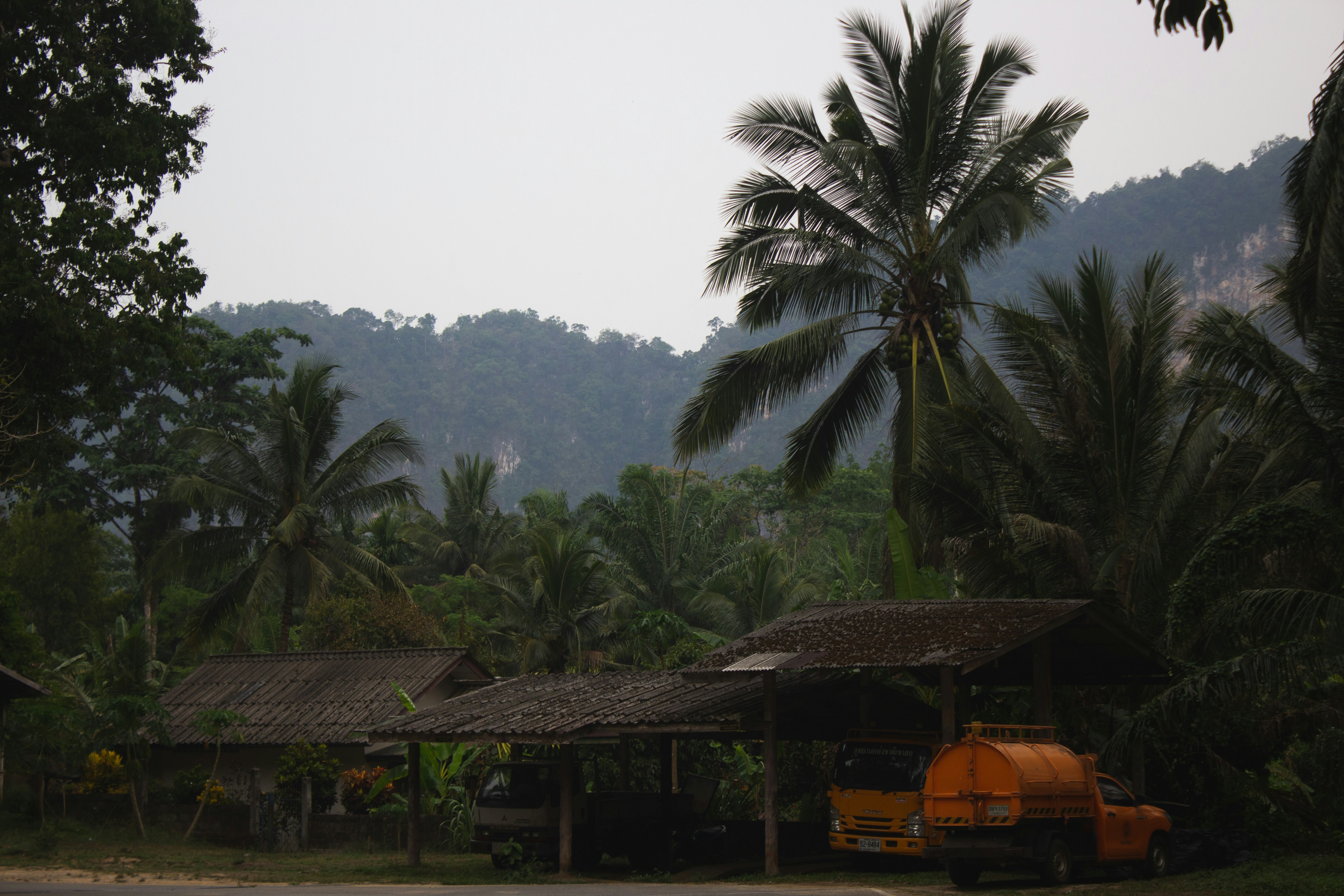 a yellow truck parked in front of a hut