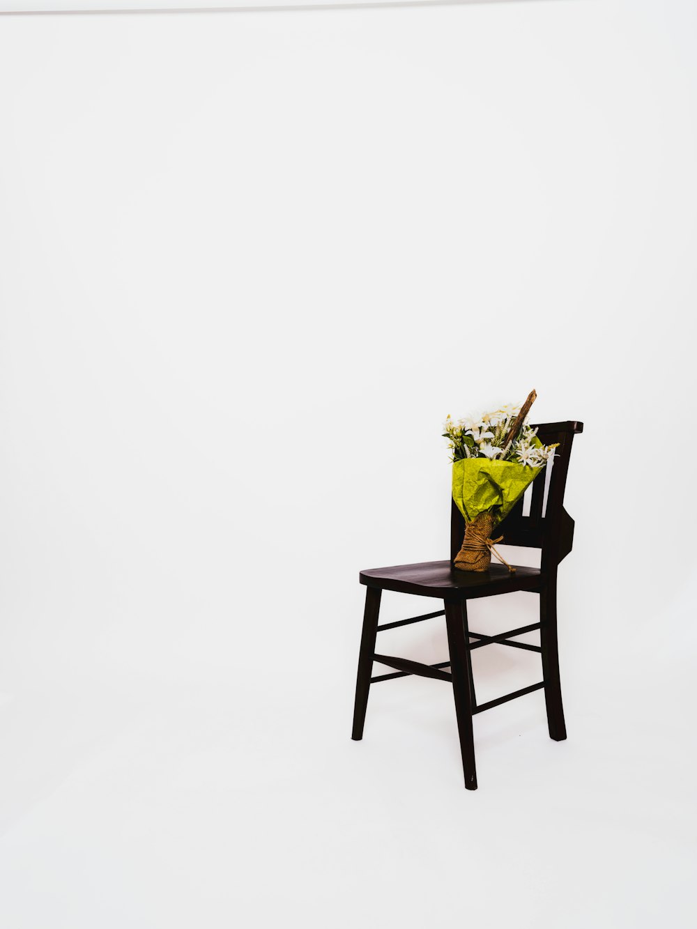 a wooden chair with a vase of flowers on it
