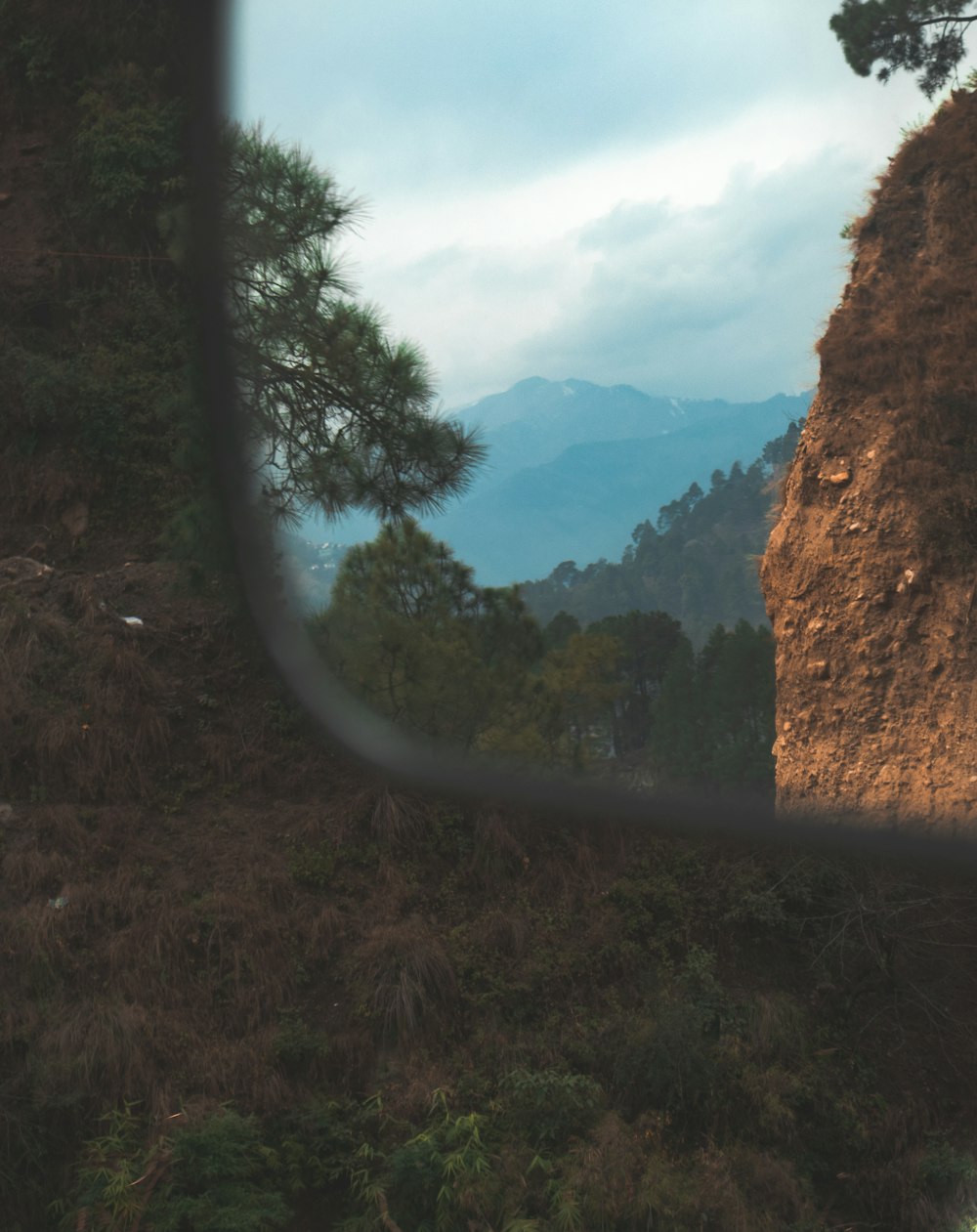 a side view mirror on a vehicle with a mountain in the background