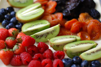 a white plate topped with sliced kiwis and berries