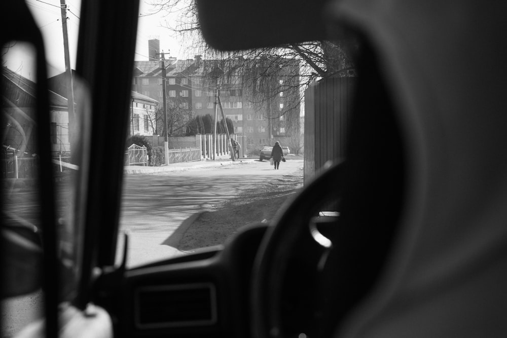 a view of a person walking down a street from inside a car