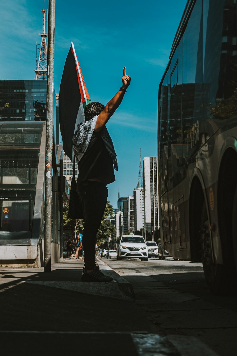 a man standing on the side of a road holding a flag