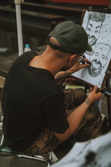 a man sitting in front of a drawing on a easel