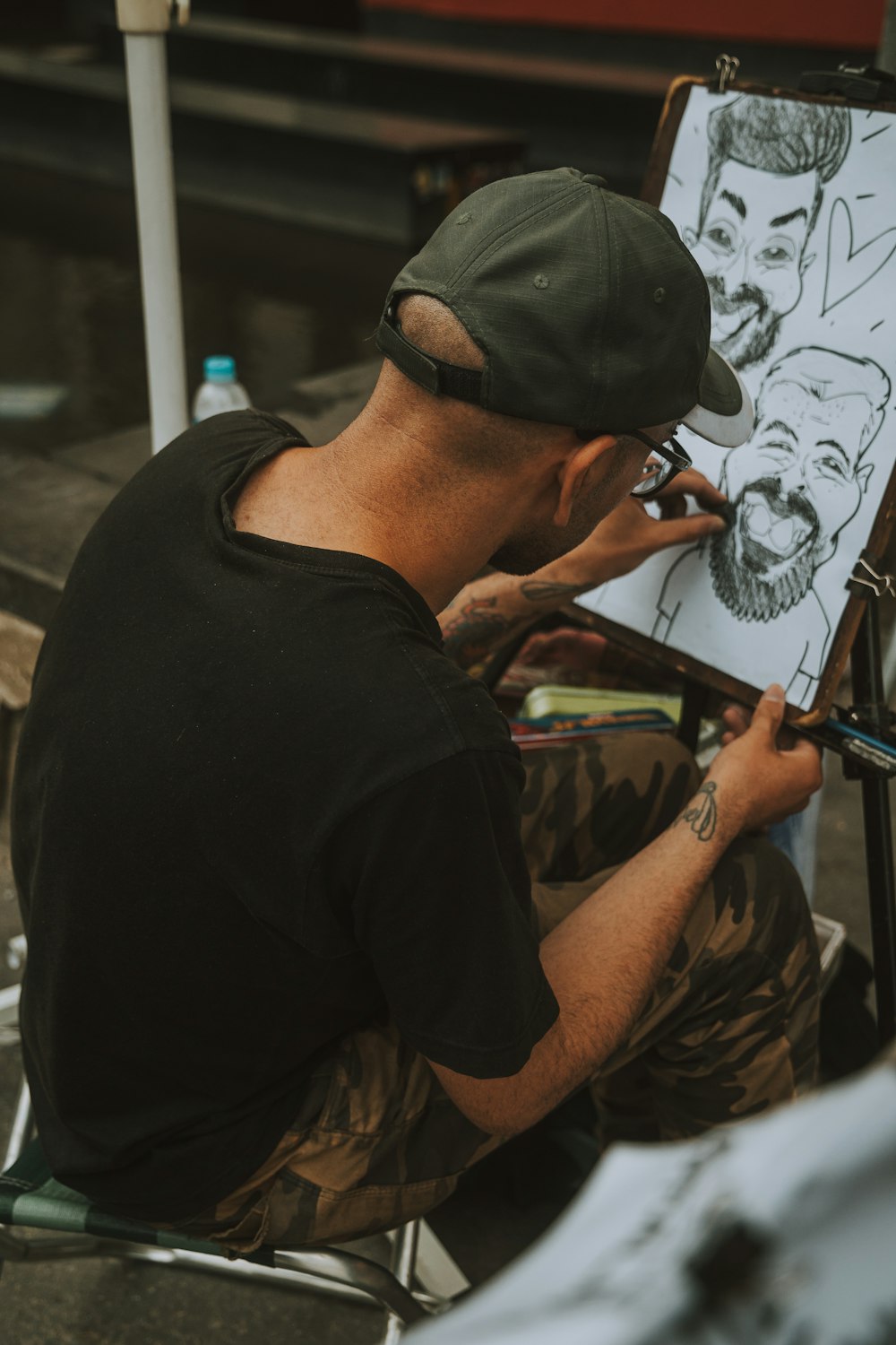 Ein Mann sitzt vor einer Zeichnung auf einer Staffelei