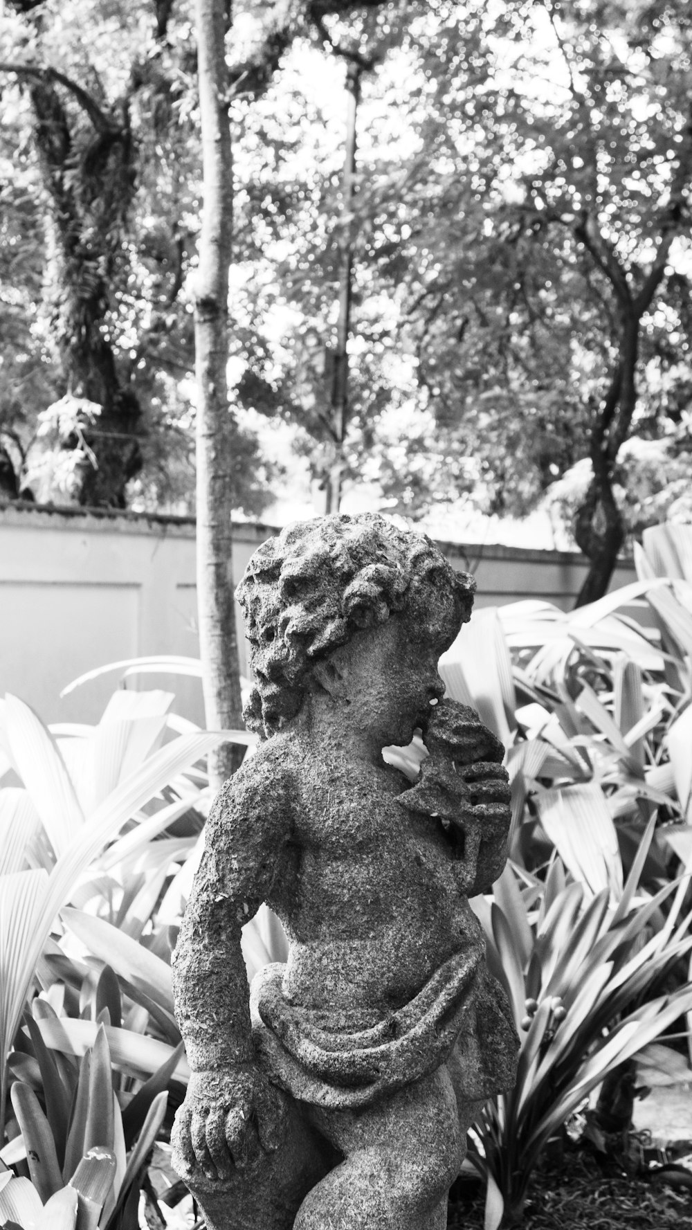 a black and white photo of a statue in a garden