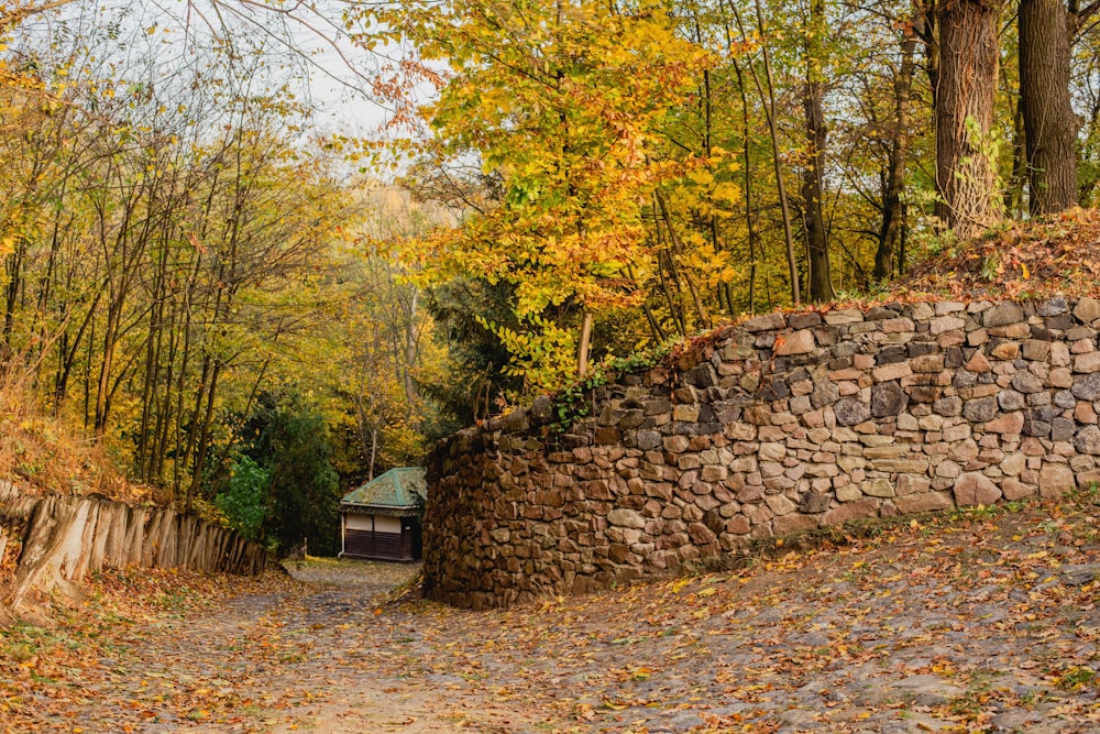 a stone wall next to a dirt road