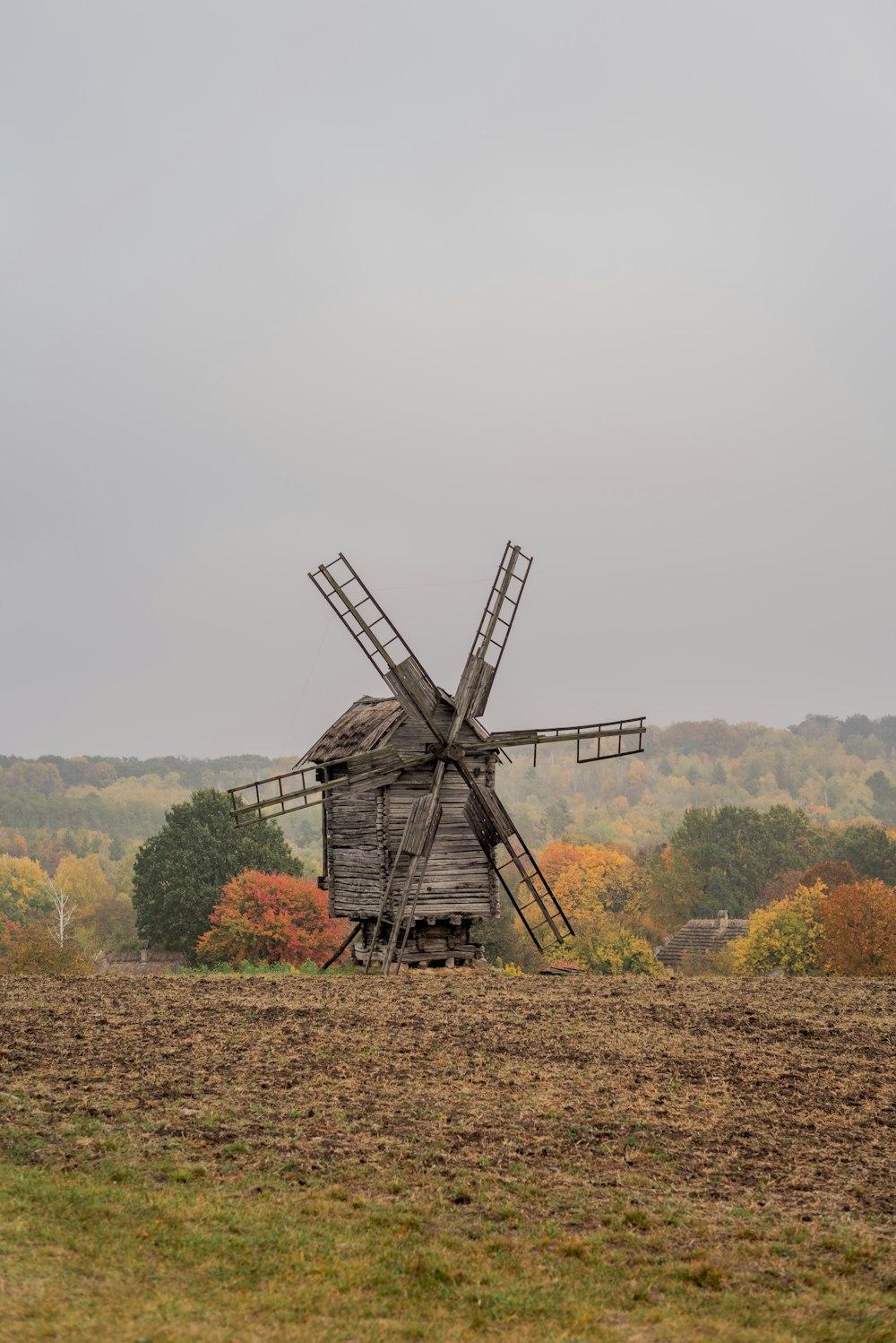 a windmill in a field with trees in the background