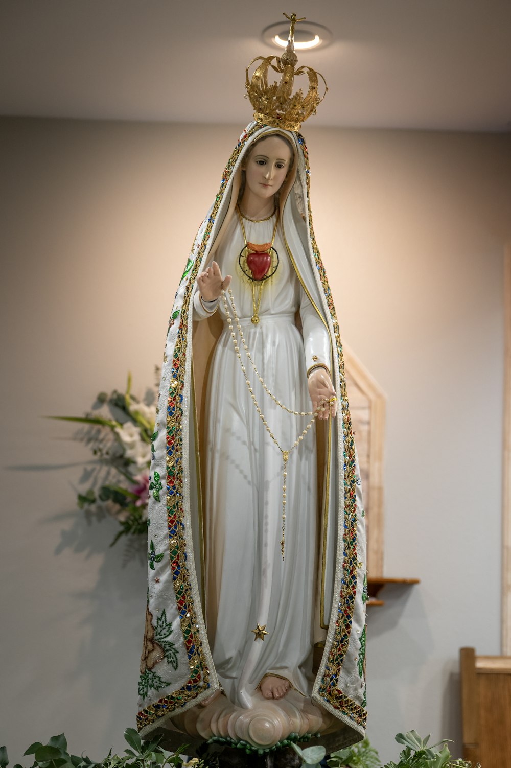 a statue of the virgin mary holding a rose