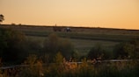 Sunset over a peaceful farm with tractors parked near barns.