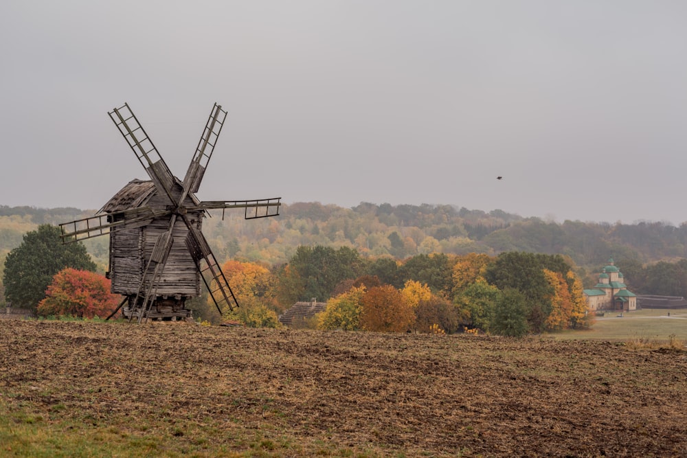 a windmill in a field with trees in the background