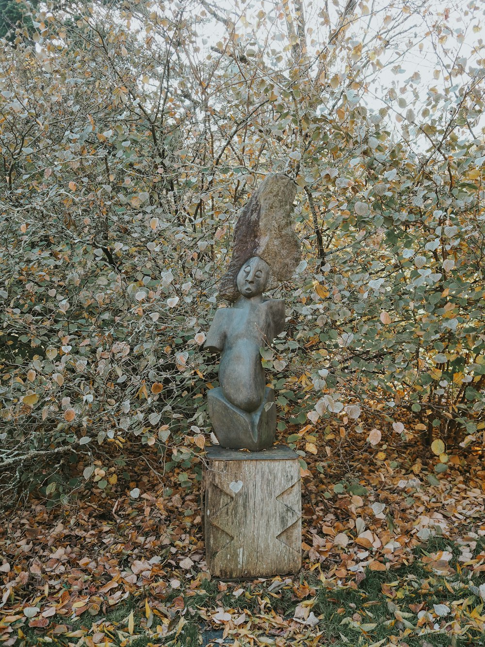 a statue of a woman sitting on top of a tree stump