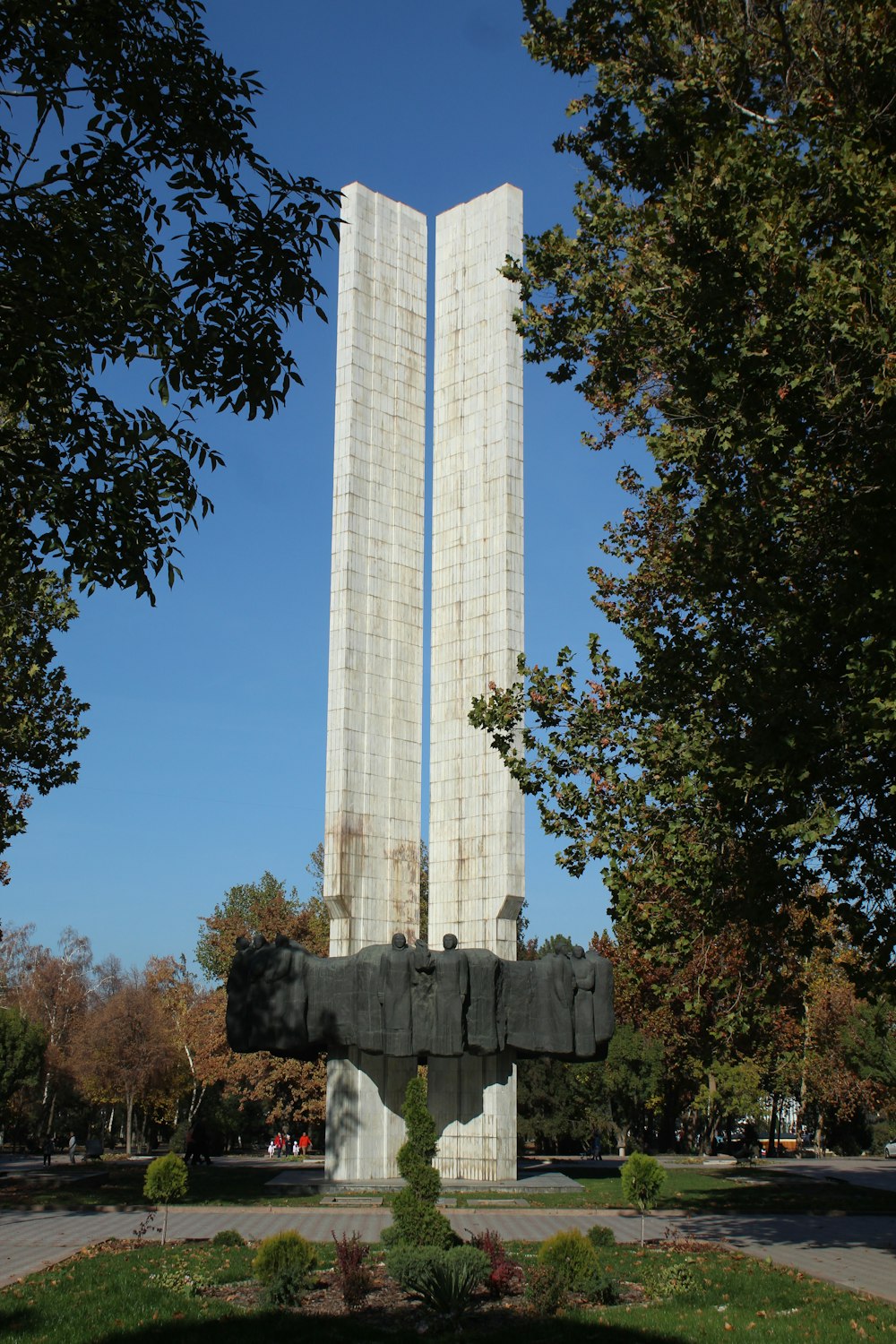 a monument with two tall towers in the middle of a park