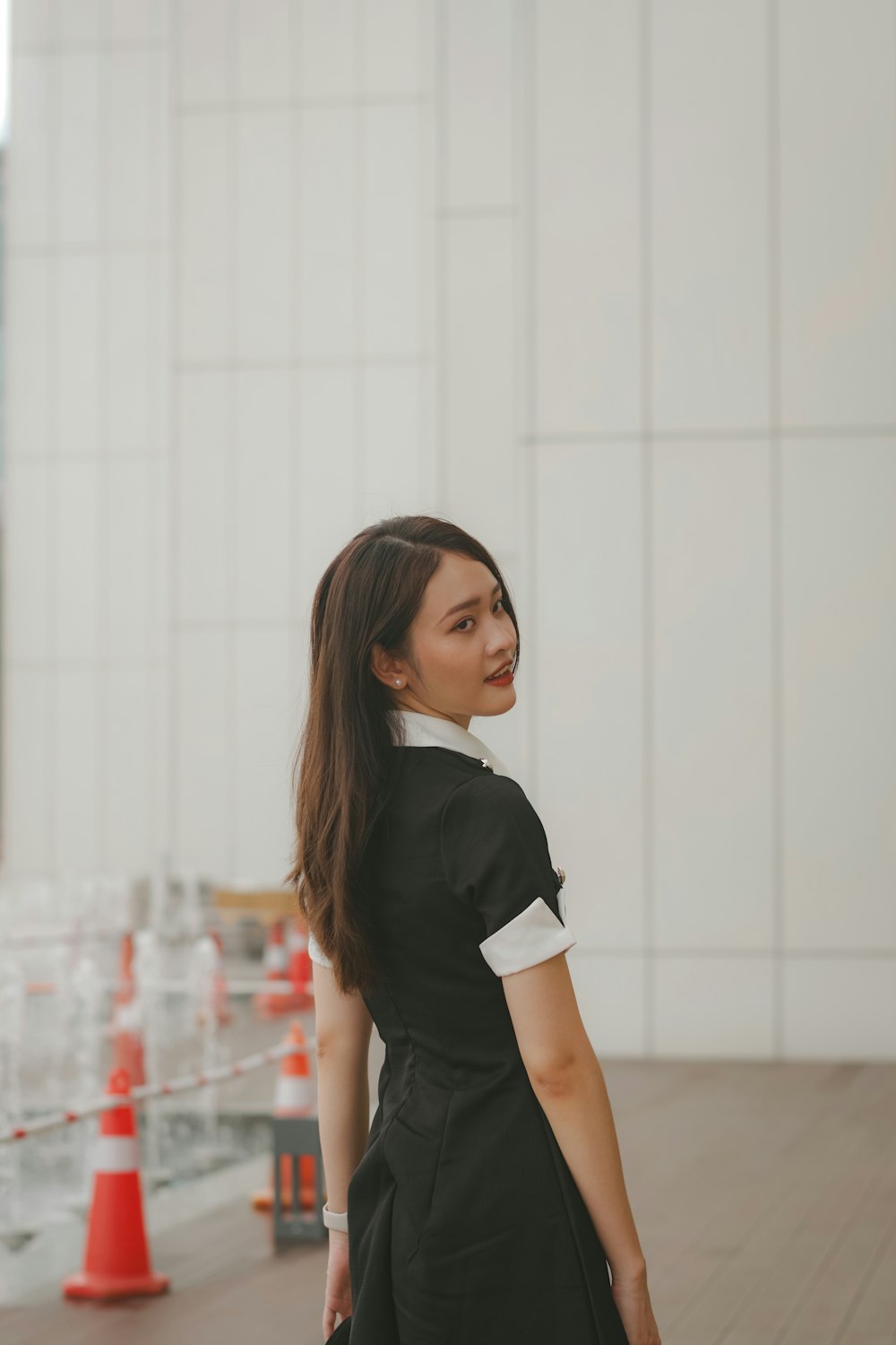 a woman in a black dress is standing on a wooden floor