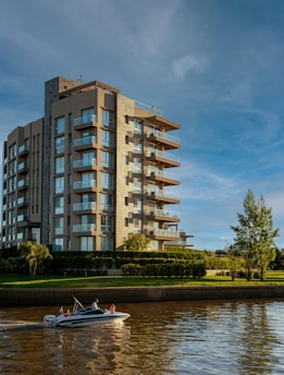 a boat traveling down a river next to a tall building